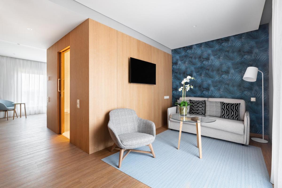 uma sala de estar com um sofá e uma mesa com uma cadeira em Eurostars Matosinhos em Matosinhos