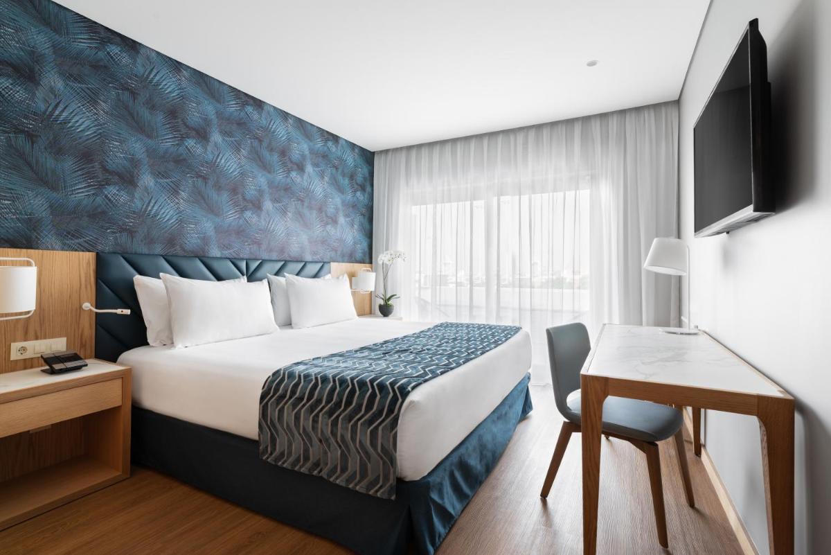 um quarto de hotel com uma cama, uma escrivaninha e uma TV em Eurostars Matosinhos em Matosinhos