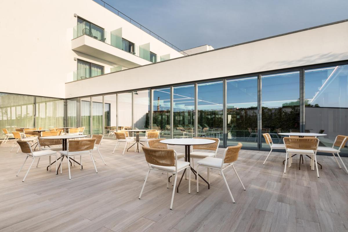 uma cafetaria com mesas, cadeiras e janelas em Eurostars Matosinhos em Matosinhos