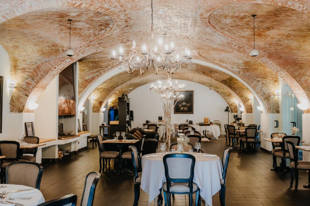 un restaurant avec des tables, des chaises et un lustre dans l'établissement Hôtel La Robéyère - BW Signature Collection, à Embrun