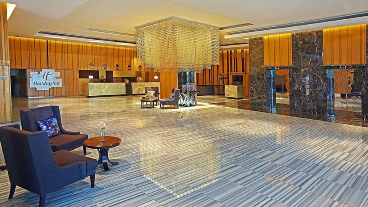 a lobby with chairs and a chandelier in a building at Holiday Inn New Delhi Mayur Vihar Noida by IHG in New Delhi a lobby with chairs and a chandelier in a building at Holiday Inn New Delhi Mayur Vihar Noida by IHG in New Delhi