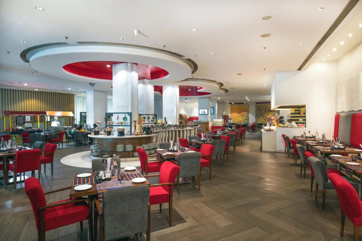 a dining room with tables and red chairs at Welcomhotel by ITC Hotels, Dwarka, New Delhi in New Delhi a dining room with tables and red chairs at Welcomhotel by ITC Hotels, Dwarka, New Delhi in New Delhi