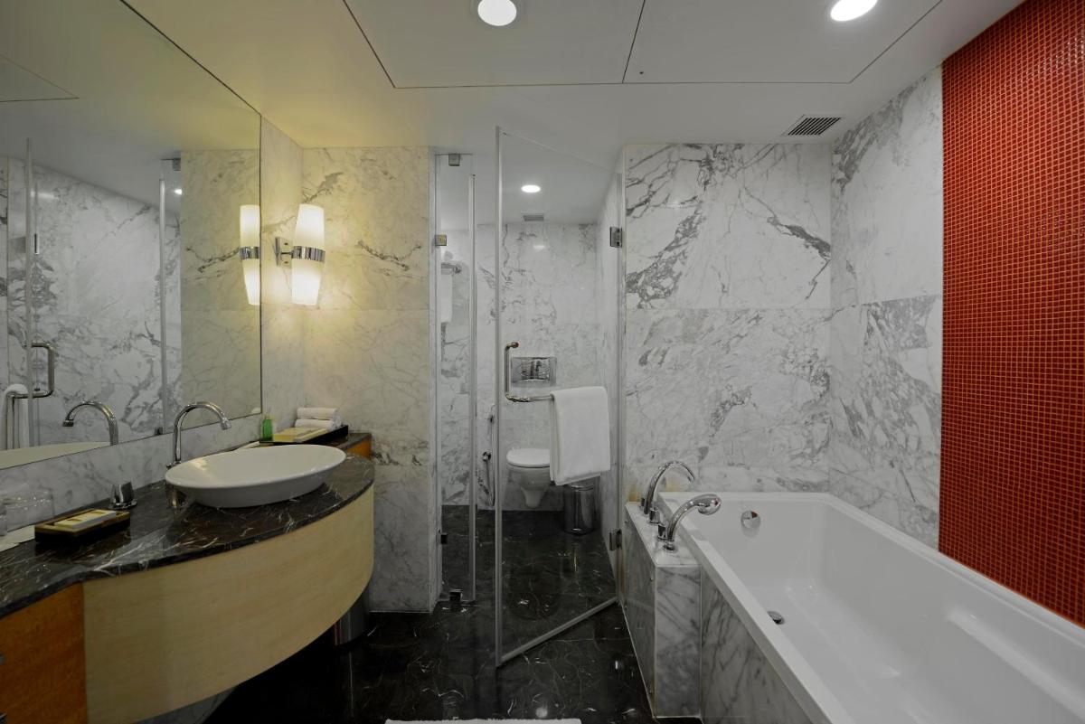 a bathroom with a sink and a shower and a tub at Radisson Blu Hotel Ahmedabad in Ahmedabad
