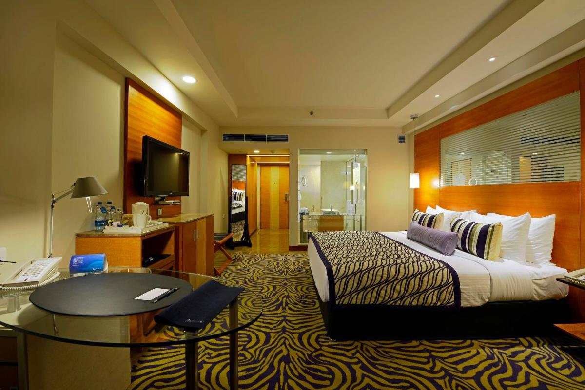 a hotel room with a bed and a desk at Radisson Blu Hotel Ahmedabad in Ahmedabad