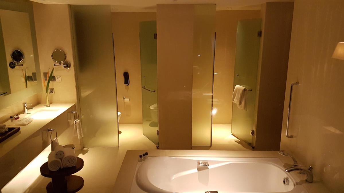 a bathroom with a tub and a shower and a sink at Crowne Plaza Kochi by IHG in Cochin