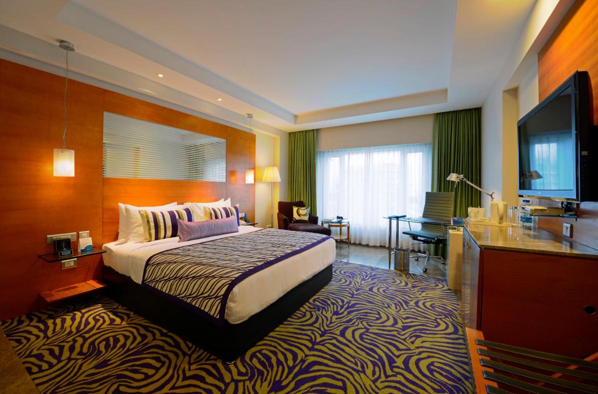 a hotel room with a bed and a flat screen tv at Radisson Blu Hotel Ahmedabad in Ahmedabad