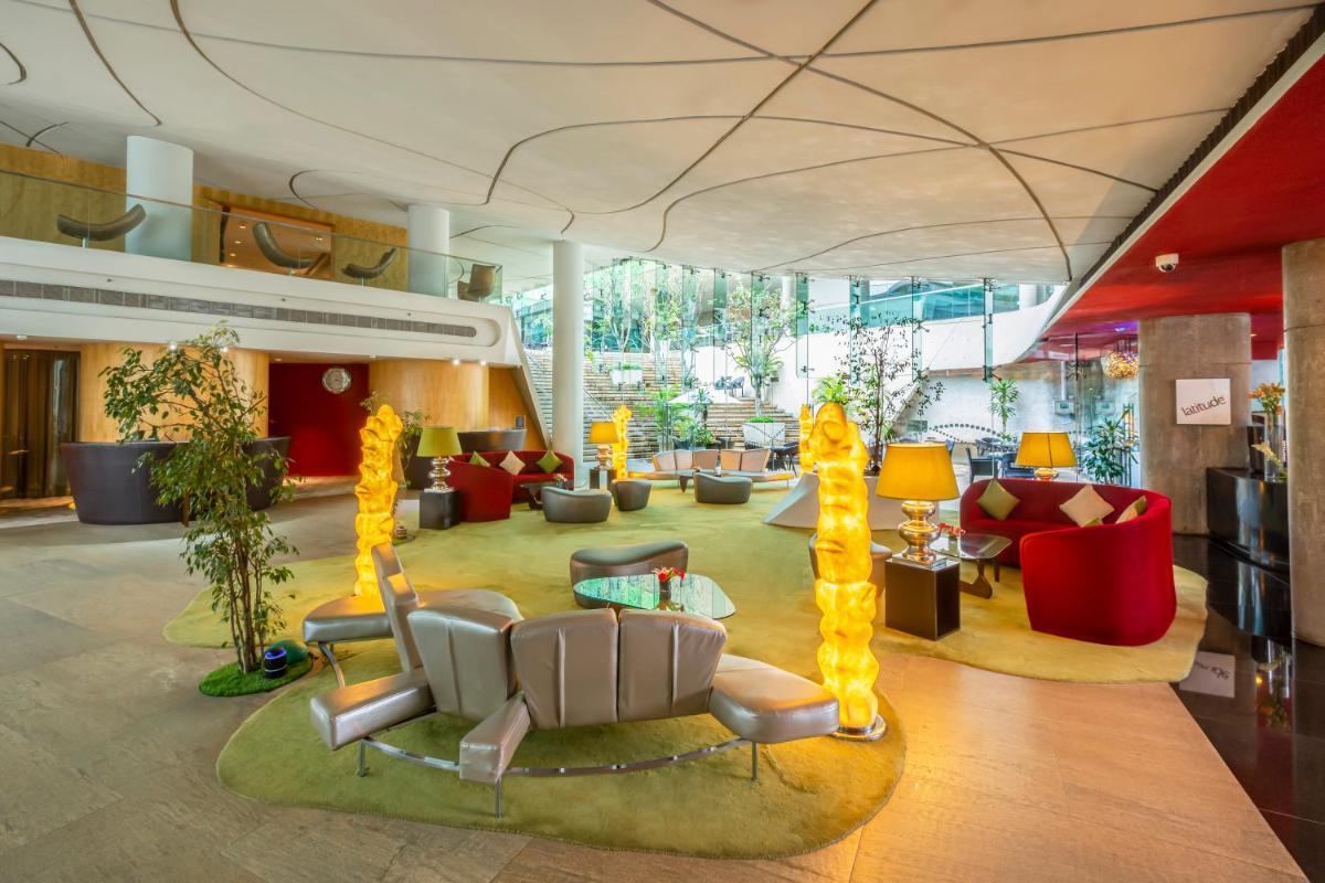 a lobby with couches and chairs in a building at Vivanta Bengaluru, Whitefield in Bengaluru