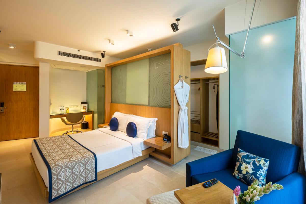 a hotel room with a bed and a blue couch at Vivanta Bengaluru, Whitefield in Bengaluru