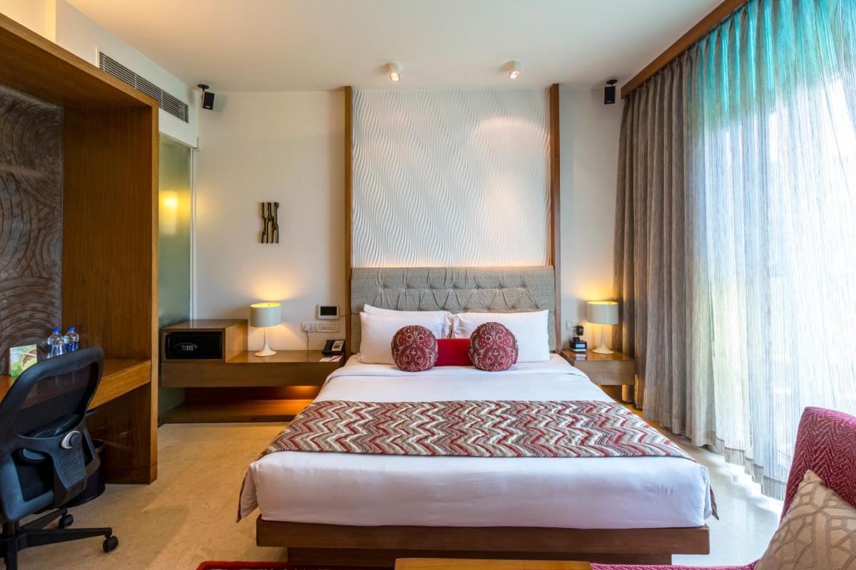 a hotel room with a large bed with red pillows at Vivanta Bengaluru, Whitefield in Bengaluru