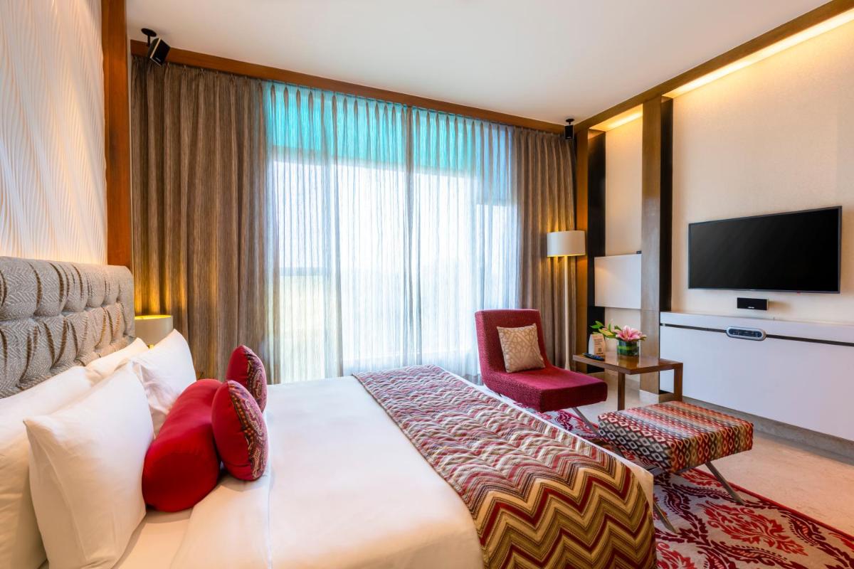 a hotel room with a bed and a television at Vivanta Bengaluru, Whitefield in Bengaluru