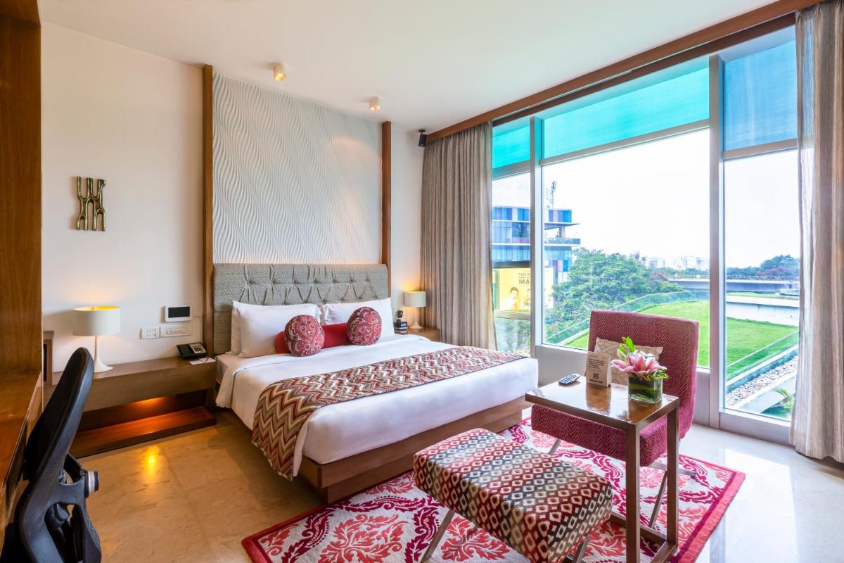 a hotel room with a bed and a large window at Vivanta Bengaluru, Whitefield in Bengaluru