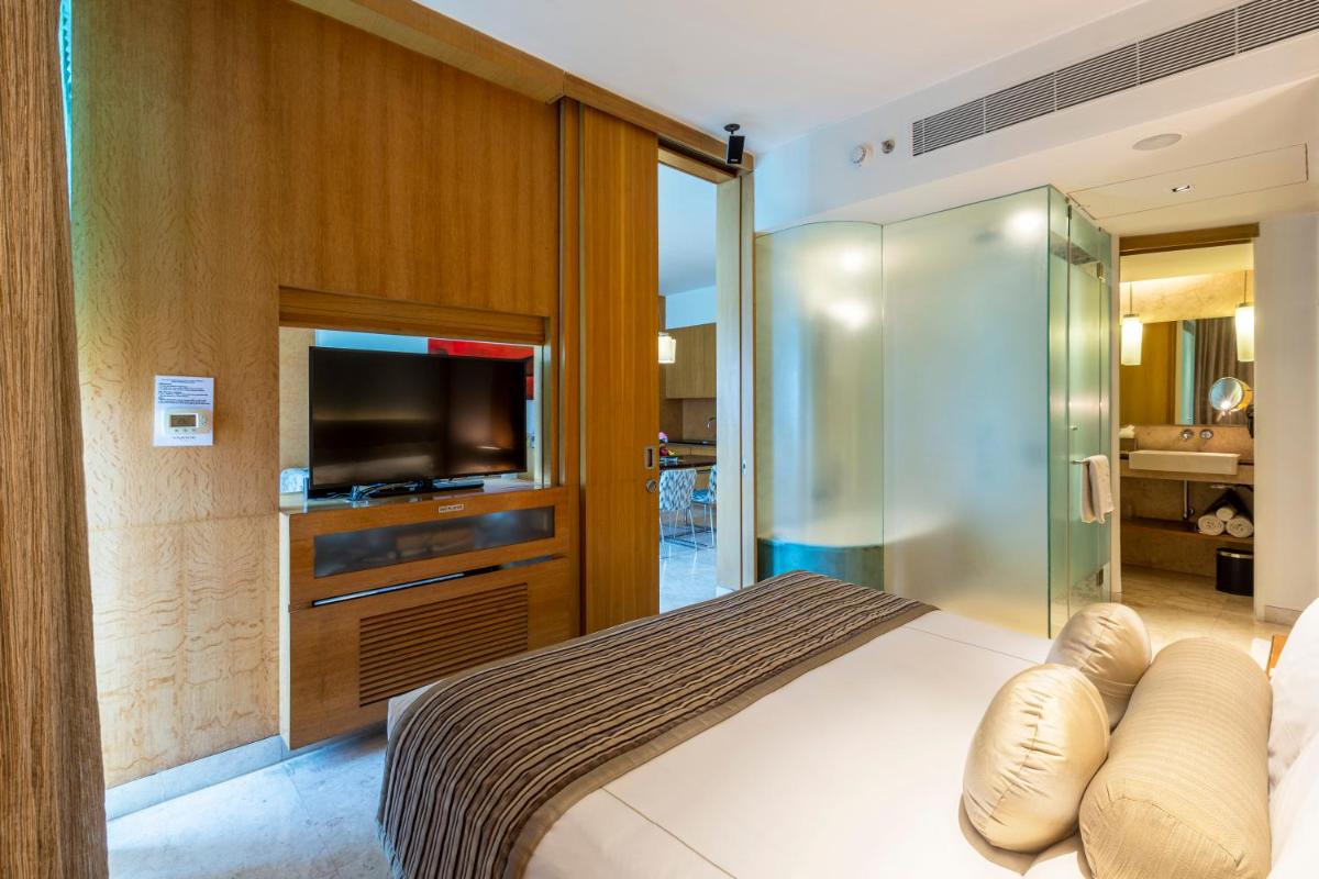 a bedroom with a bed with a tv and a sliding glass door at Vivanta Bengaluru, Whitefield in Bengaluru