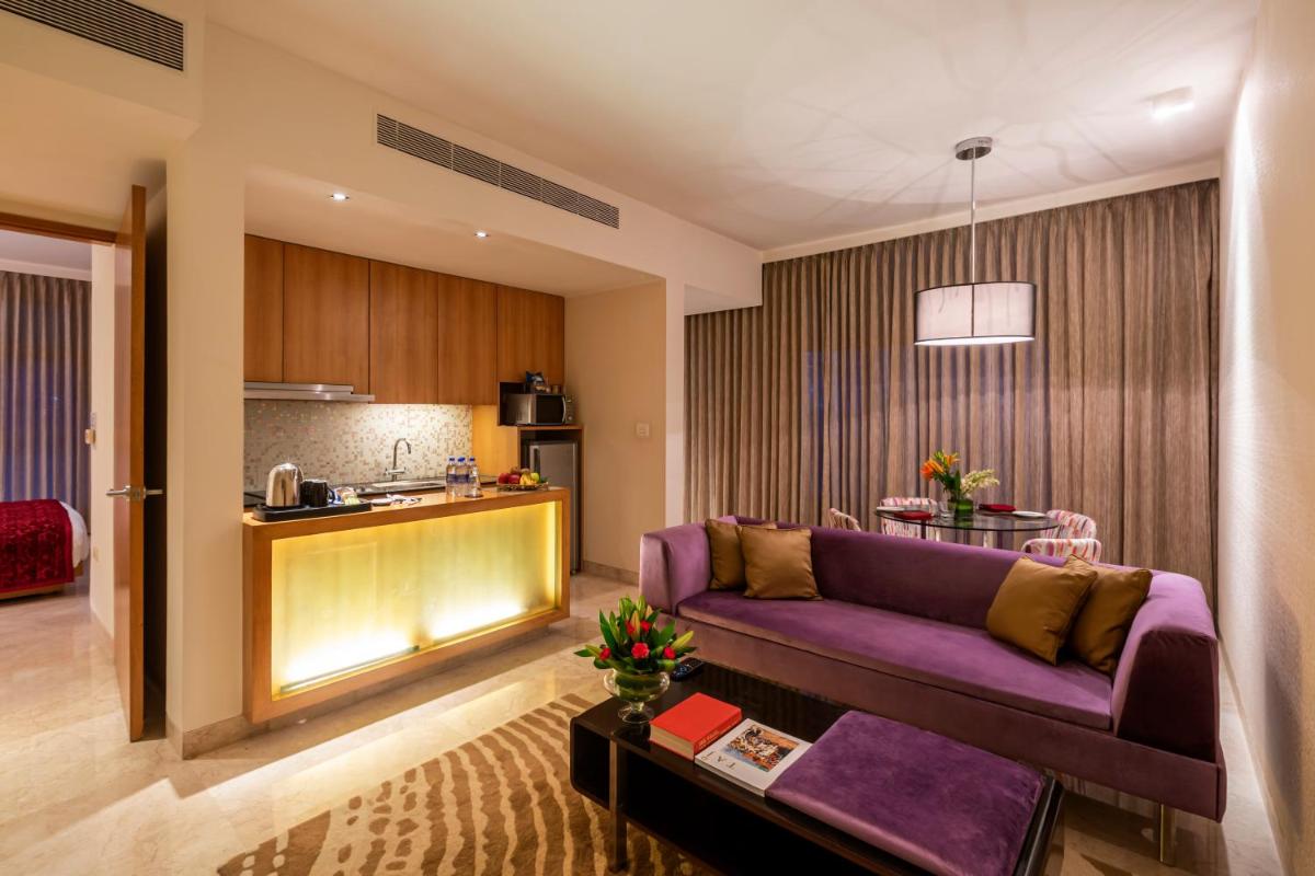 a living room with a purple couch and a kitchen at Vivanta Bengaluru, Whitefield in Bengaluru