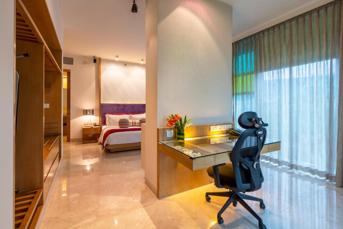 a room with a desk and a bedroom with a bed at Vivanta Bengaluru, Whitefield in Bengaluru