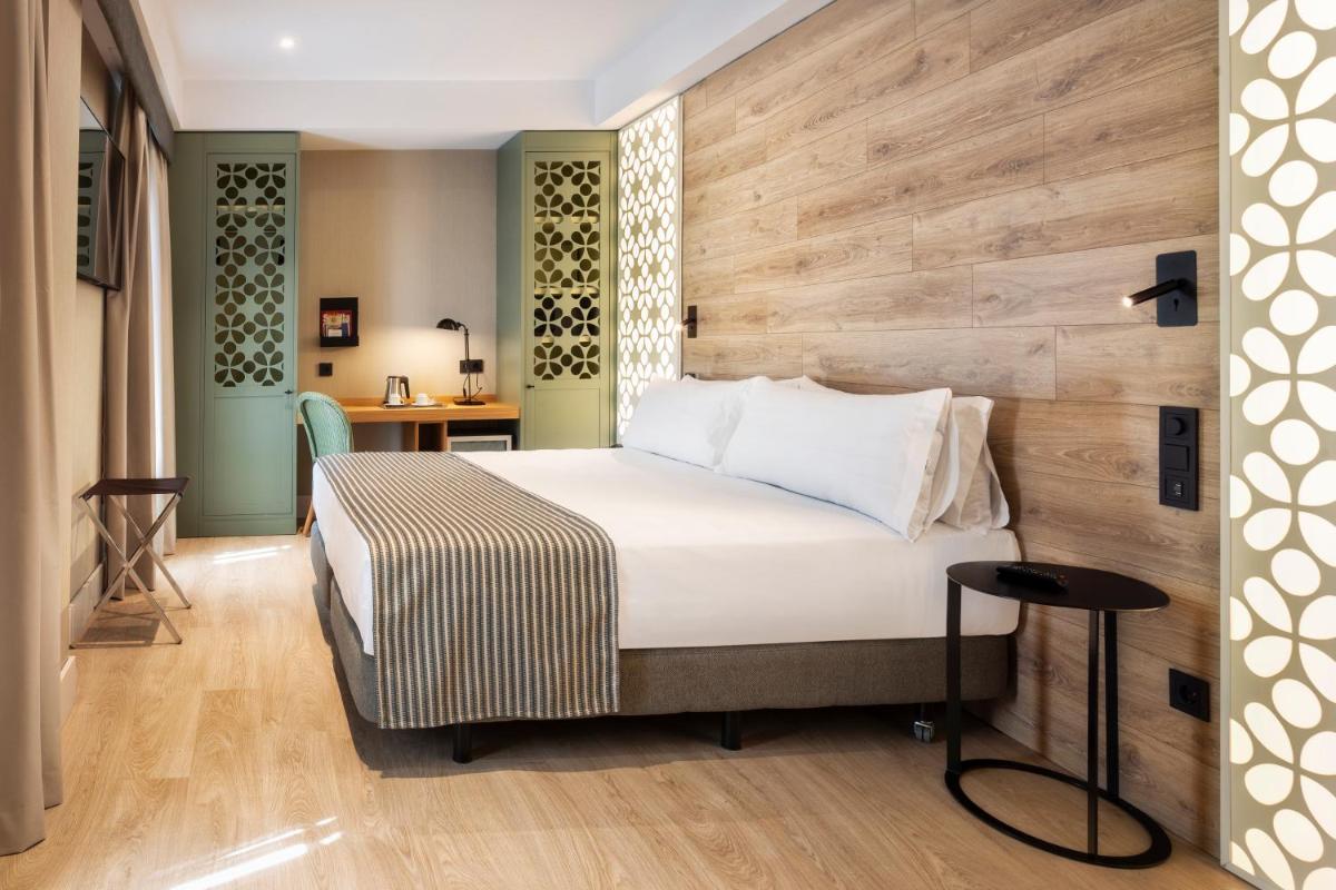 Un dormitorio con una cama y una pared de madera. en Catalonia Santa Justa, en Sevilla
