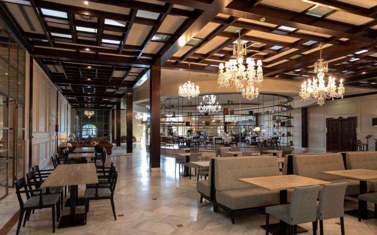 Un restaurante con mesas, sillas y lámparas de araña. en Hotel Doña Brígida – Salamanca Forum, en Villamayor