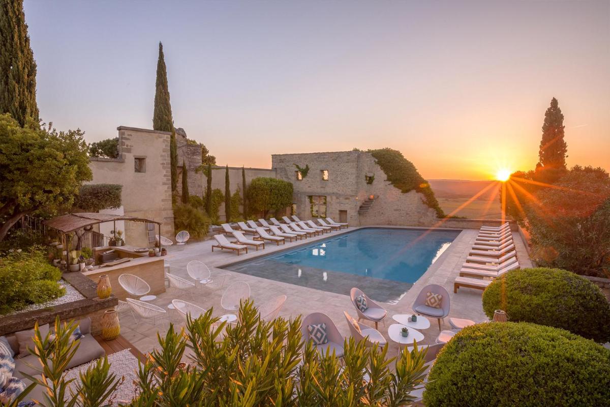 une villa avec une piscine en face d'un coucher de soleil dans l'établissement Le Vieux Castillon, à Castillon-du-Gard