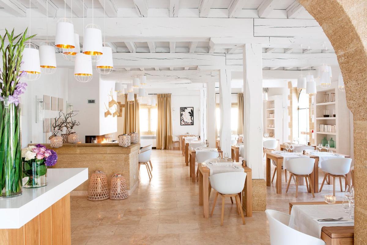 un restaurant avec des tables blanches et des chaises blanches dans l'établissement Le Vieux Castillon, à Castillon-du-Gard