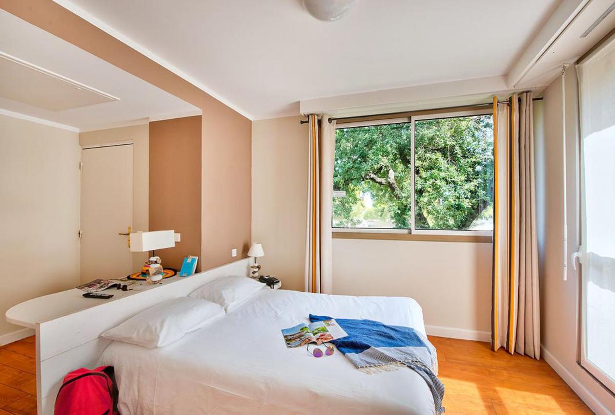 une chambre avec un lit blanc et une fenêtre dans l'établissement Hôtel Club la Font des Horts, à Hyères