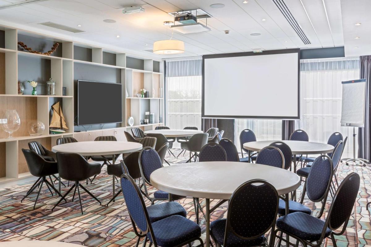 une salle de conférence avec des tables, des chaises et un écran de projection dans l'établissement Best Western Plus Europe Hôtel Brest, à Brest 82 autres photos