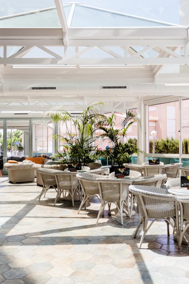 Un vestíbulo con mesas, sillas y plantas. en KAKTUS Hotel Kaktus Playa - Adults Recommended, en Calella