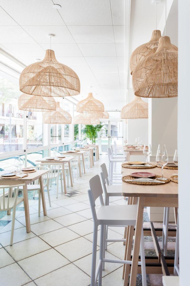 Un restaurante con mesas, sillas y sombrillas. en KAKTUS Hotel Kaktus Playa - Adults Recommended, en Calella