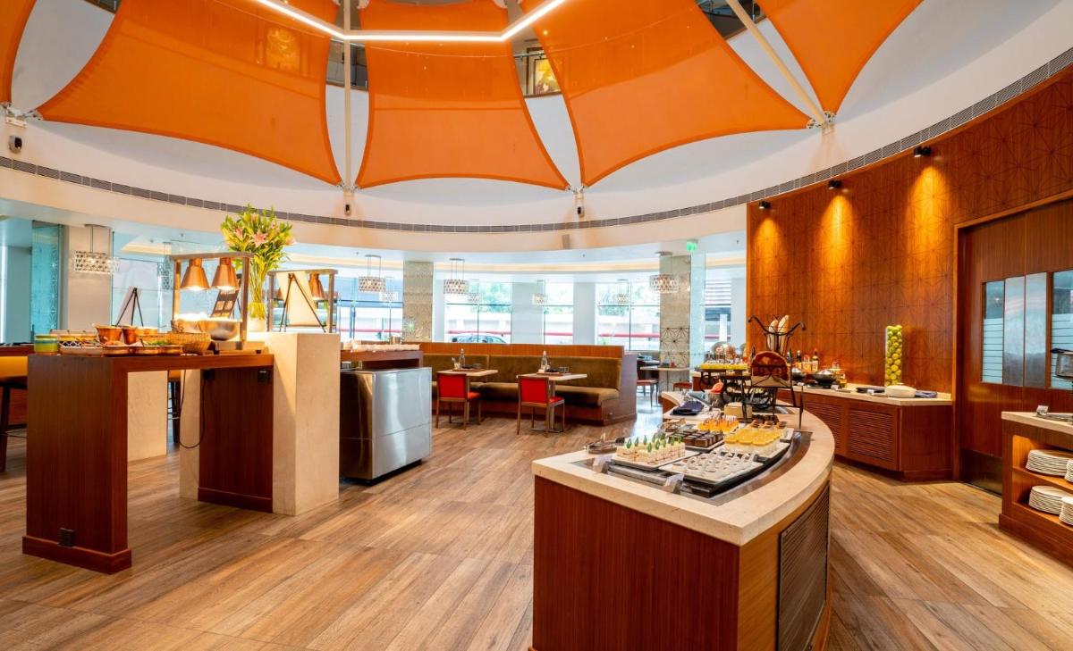 an open kitchen and dining room with an orange ceiling at Hyatt Place Hyderabad Banjara Hills in Hyderabad