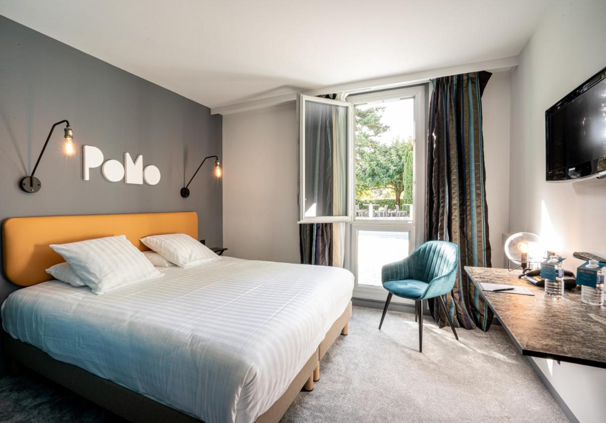 une chambre avec un lit, un bureau et une fenêtre dans l'établissement PoMo Hôtel & Restaurant, à Échirolles