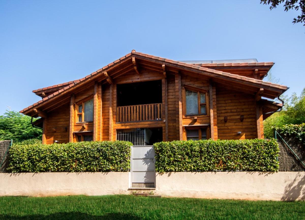 una casa de madera con una valla delante en Hotel Somlom - ECO Friendly Montseny, en Sant Esteve de Palautordera una casa de madera con una valla delante en Hotel Somlom - ECO Friendly Montseny, en Sant Esteve de Palautordera