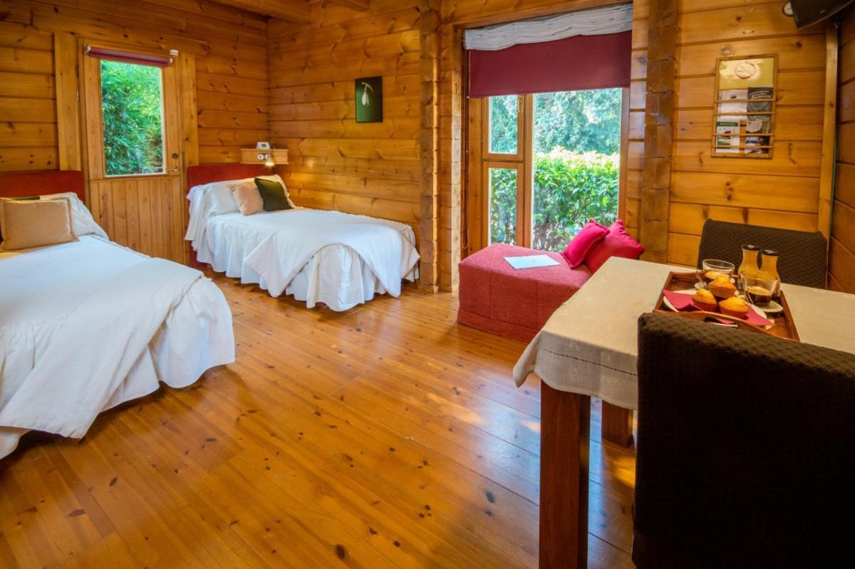 una habitación con 2 camas y una mesa en una cabaña en Hotel Somlom - ECO Friendly Montseny, en Sant Esteve de Palautordera