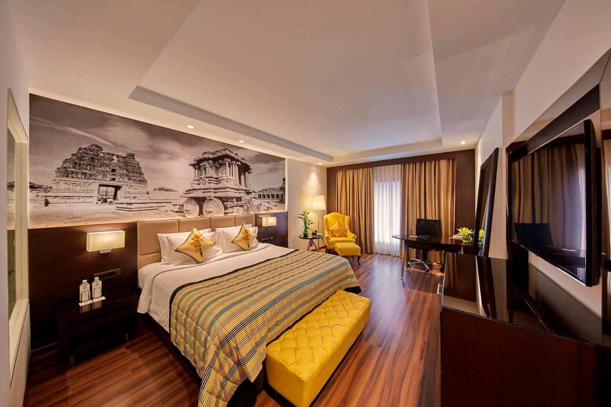 a hotel room with a bed and a tv at Hotel Royal Orchid Bangalore in Bengaluru