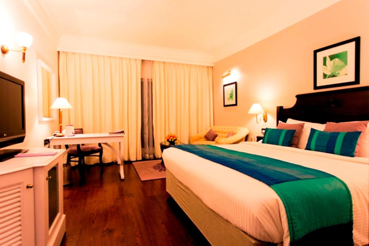 a hotel room with a large bed and a television at Hotel Royal Orchid Bangalore in Bengaluru