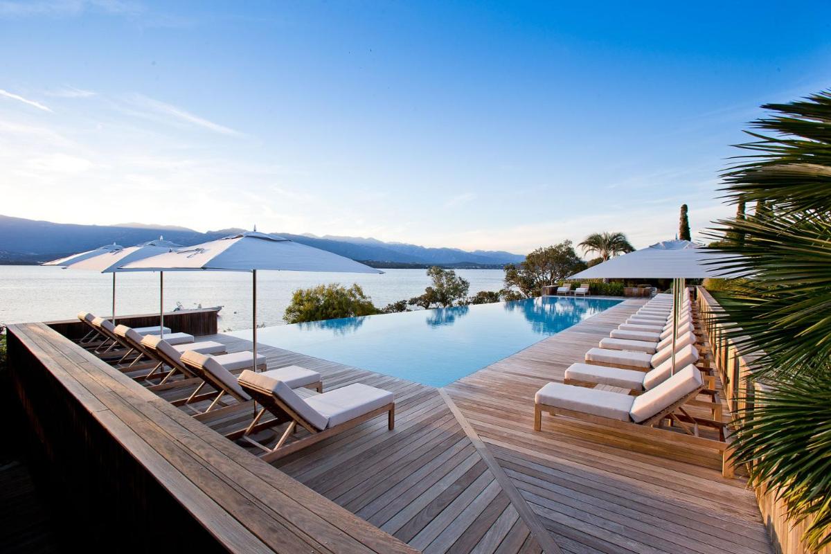 une piscine avec chaises longues et parasols sur une terrasse en bois dans l'établissement Casadelmar, à Porto-Vecchio