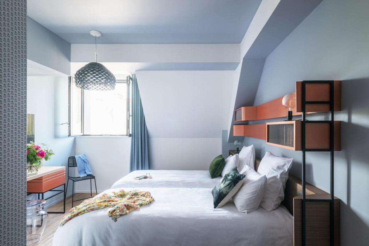 une chambre avec un lit blanc et un mur d'accent bleu dans l'établissement Golden Tulip Saint Malo– Le Grand Bé, à Saint-Malo