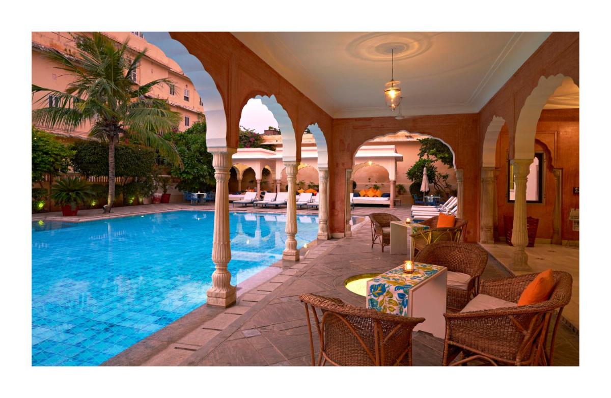 a large swimming pool in a building with chairs at Samode Haveli in Jaipur