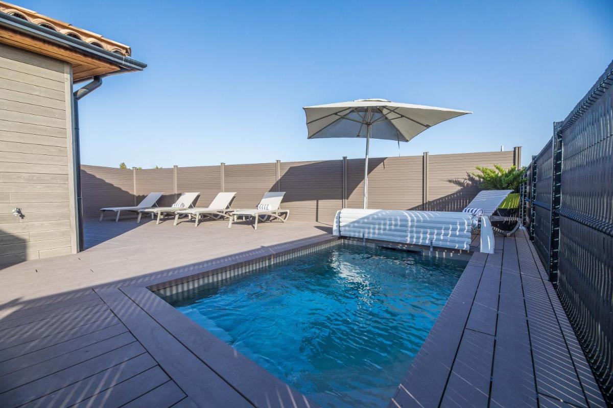 une piscine avec un parasol et quelques chaises longues et un parasol dans l'établissement Résidence Pierre & Vacances Premium Vesna Rossa, à Porto-Vecchio