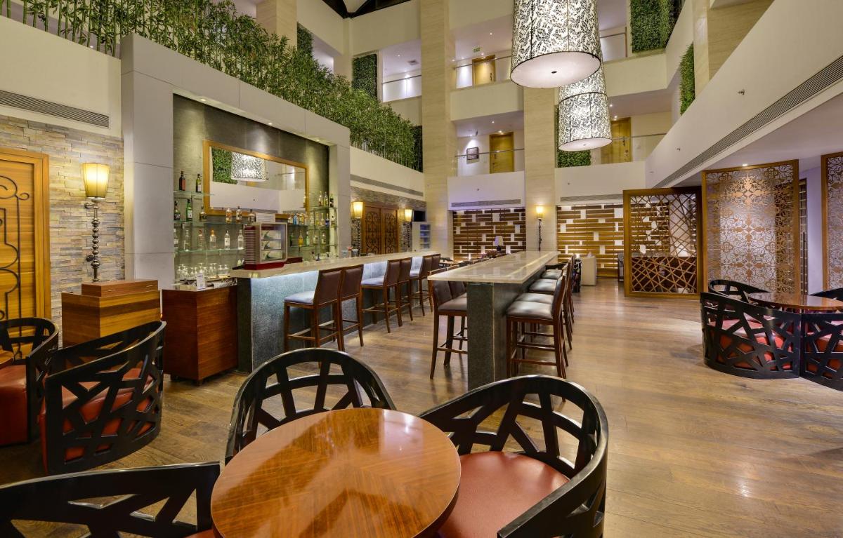 a restaurant with tables and chairs and a bar at Pride Plaza Hotel, Kolkata in Kolkata