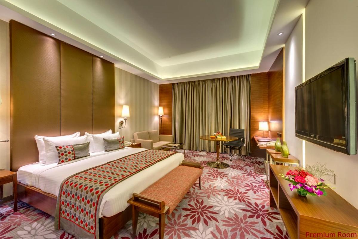 a hotel room with a bed and a flat screen tv at Pride Plaza Hotel, Kolkata in Kolkata