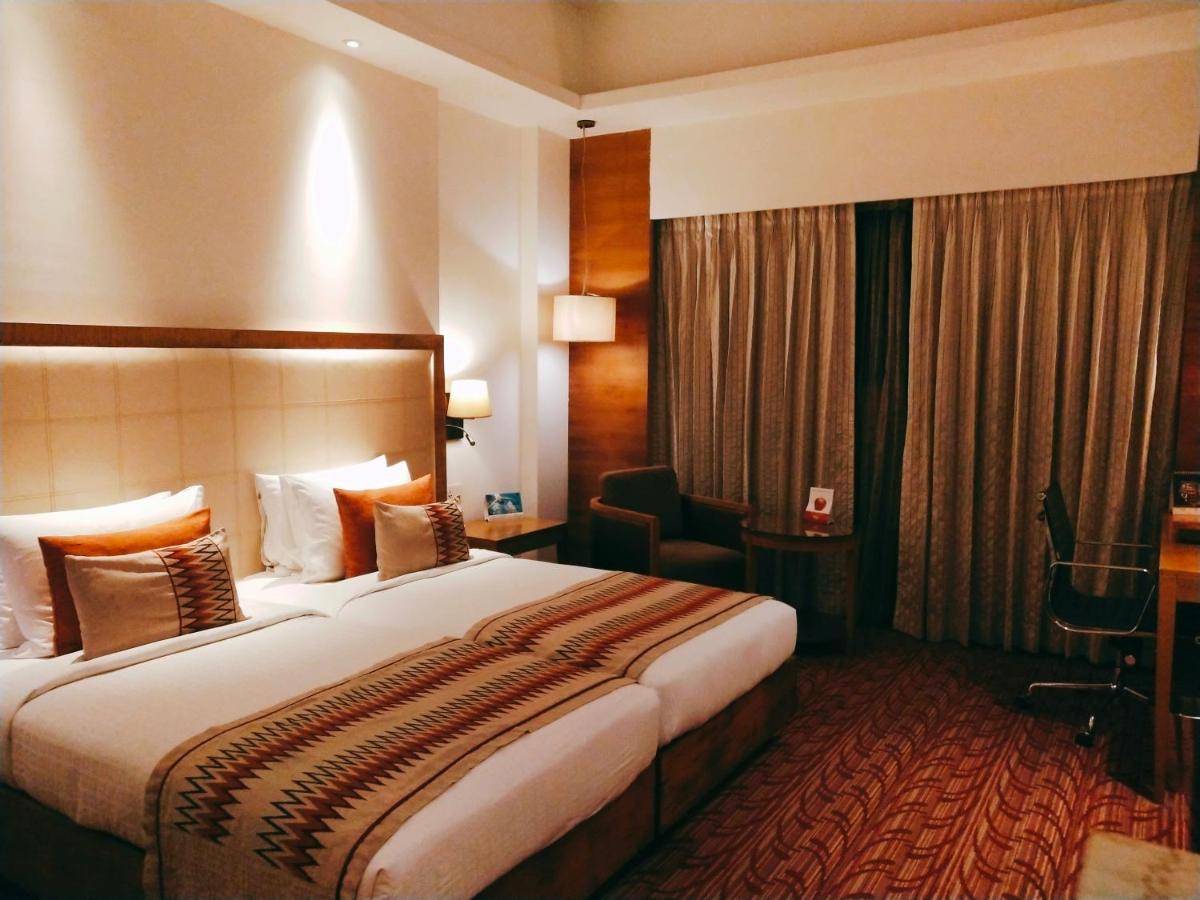 a hotel room with a large bed and a desk at Pride Plaza Hotel, Kolkata in Kolkata