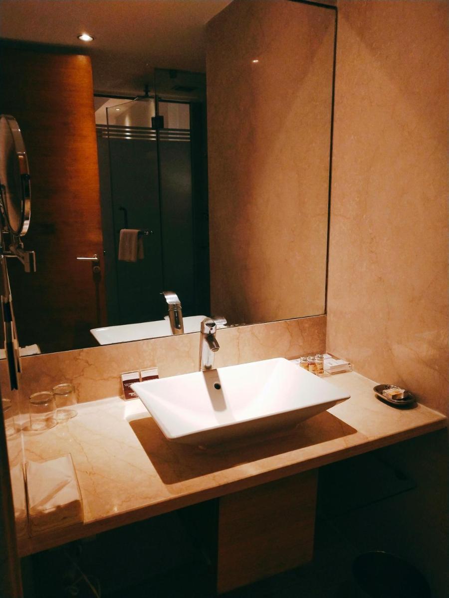 a bathroom with a sink and a large mirror at Pride Plaza Hotel, Kolkata in Kolkata