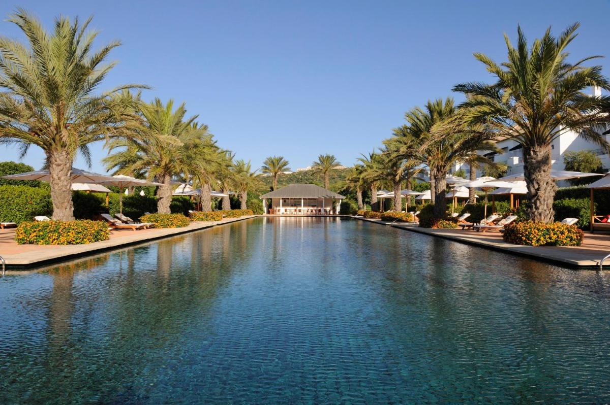 Una piscina en un resort con palmeras y sombrillas. en Finca Cortesin Hotel Golf & Spa, en Casares