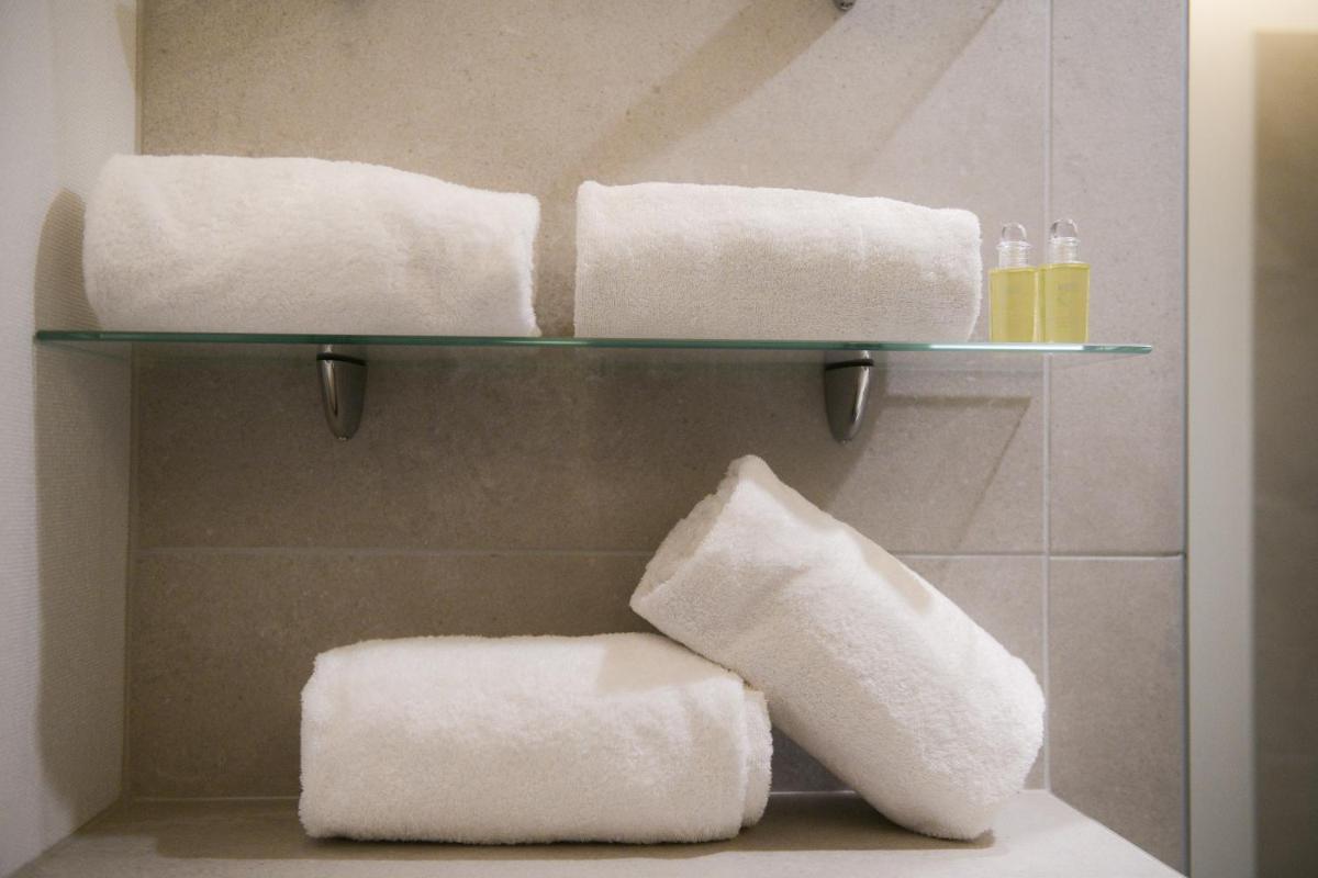 - une salle de bains avec 3 serviettes sur une étagère dans l'établissement Appart'Hotel Aiguille Verte & Spa, à Chamonix-Mont-Blanc
