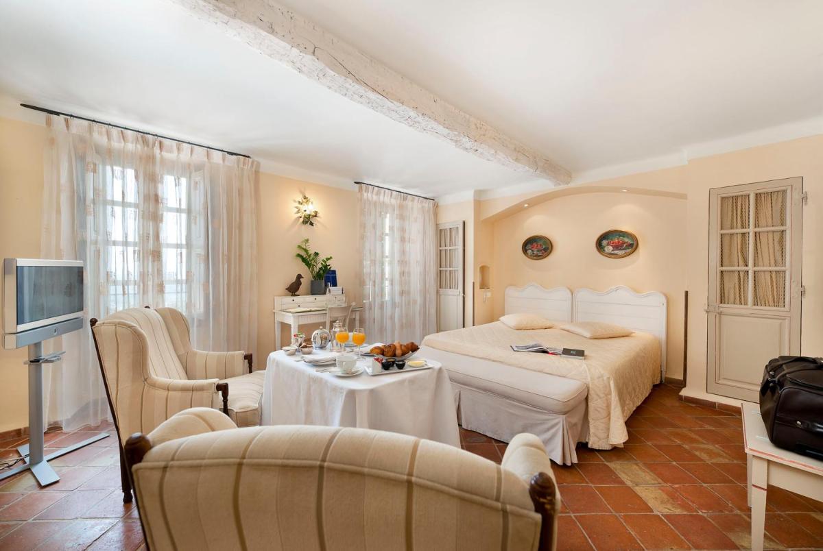 une chambre avec un lit, une table et des chaises dans l'établissement Bastide Saint Antoine - Relais & Châteaux, à Grasse