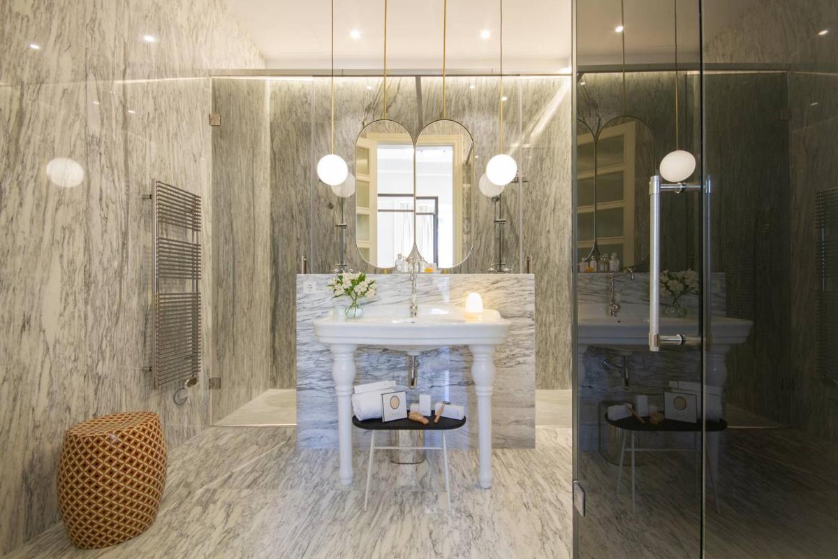 Un baño con un lavabo blanco y un espejo. en MYR Palacio Vallier, en Valencia