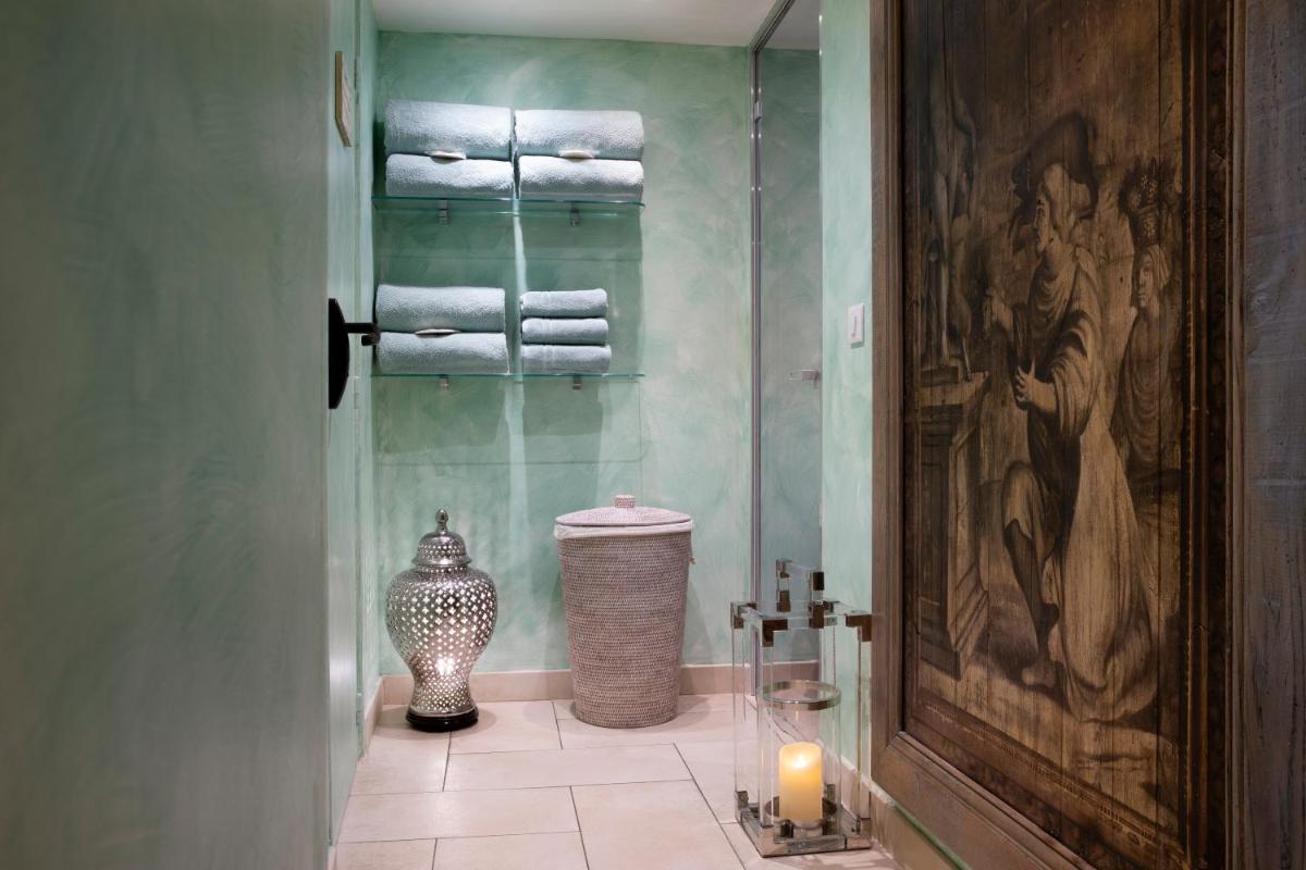 La salle de bains est pourvue d'une douche vitrée, de serviettes et d'une bougie. dans l'établissement Hotel Residence Henri IV, à Paris