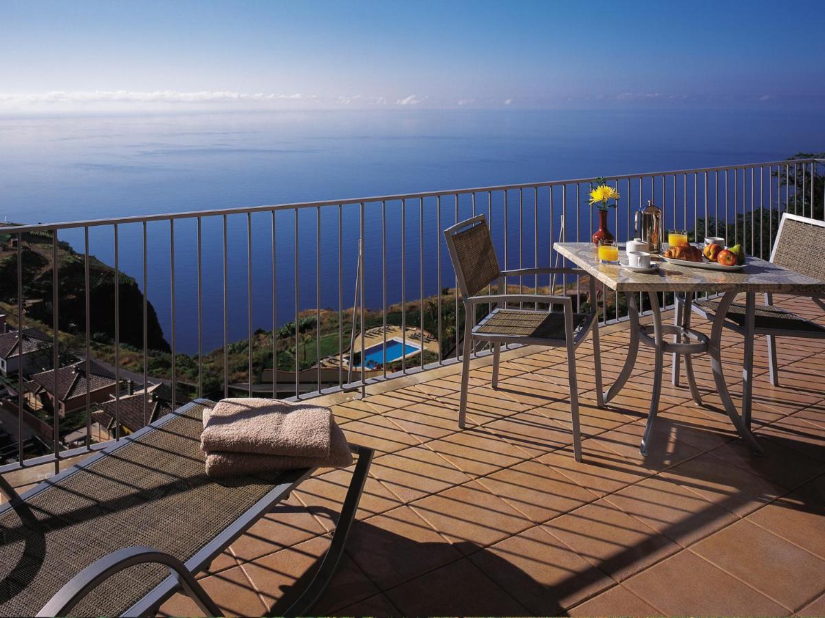 uma varanda com mesa e cadeiras e o oceano em Village Cabo Girao em Câmara de Lobos