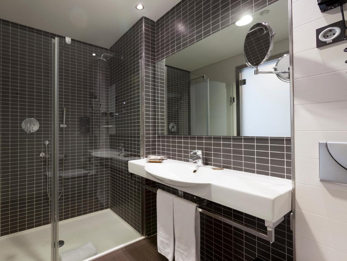 Un baño con lavabo, ducha y espejo. en Axor Feria, en Madrid