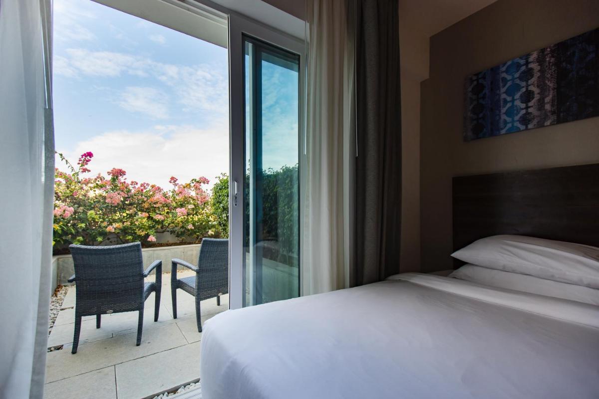 a bedroom with a bed and a view of a balcony at The Residency Towers, Rameswaram in Rāmeswaram
