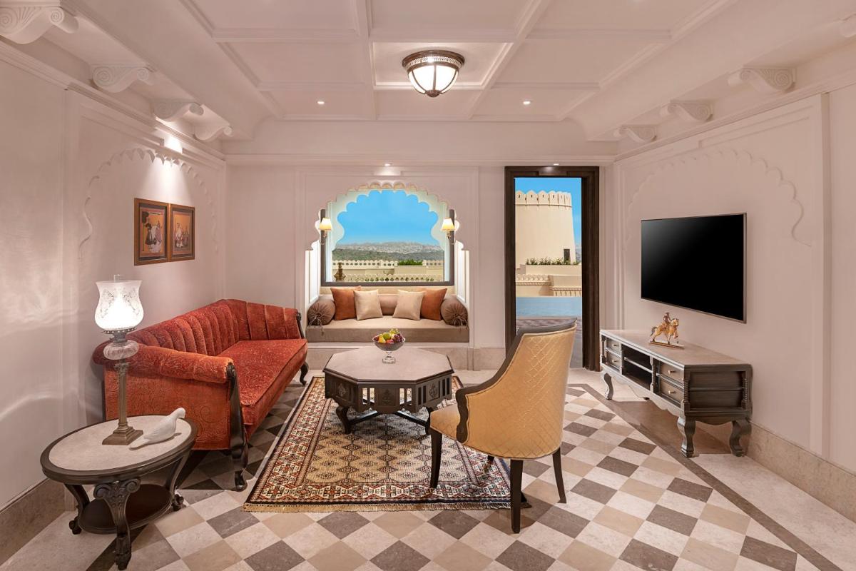 a living room with a red couch and a tv at Aurika, Udaipur - Luxury by Lemon Tree Hotels in Udaipur