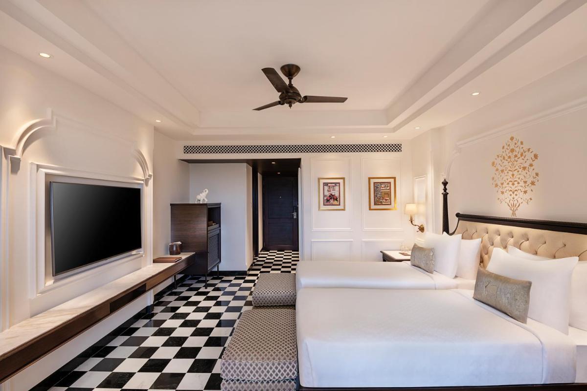 a hotel room with two beds and a flat screen tv at Aurika, Udaipur - Luxury by Lemon Tree Hotels in Udaipur